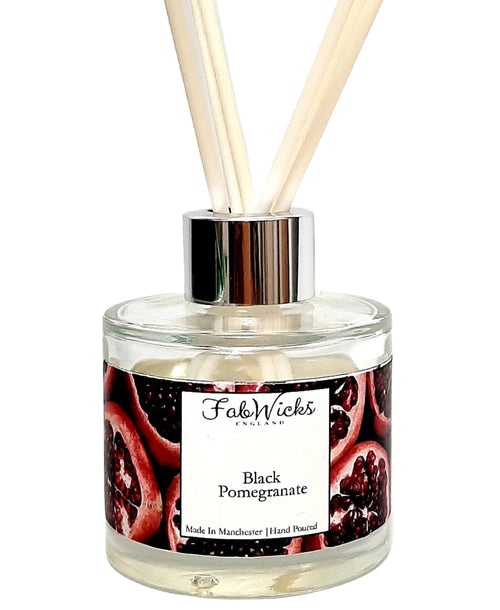 Fragrance diffuser with 'Black Pomegranate' label and wooden sticks on a white background