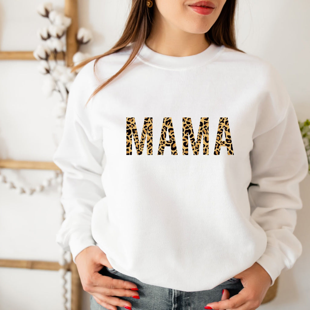 White sweatshirt with 'MAMA' in leopard print letters worn by a person.