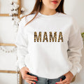 White sweatshirt with 'MAMA' in leopard print letters worn by a person.