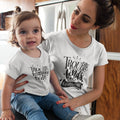 Woman and child wearing matching white t-shirts with text in a kitchen setting.