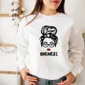 White sweatshirt with a graphic of a woman with glasses and '#MOMLIFE' text, worn by a person.